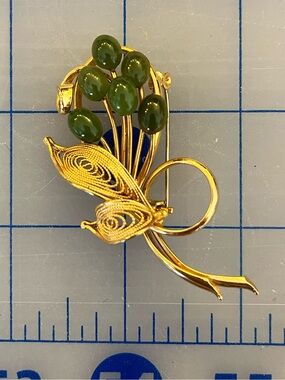 Gold coloured brooch with green stones